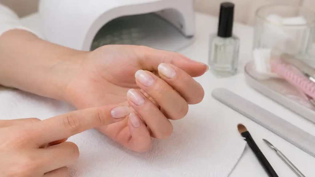 Main montrant le bord libre d’un ongle avec vernis semi-permanent