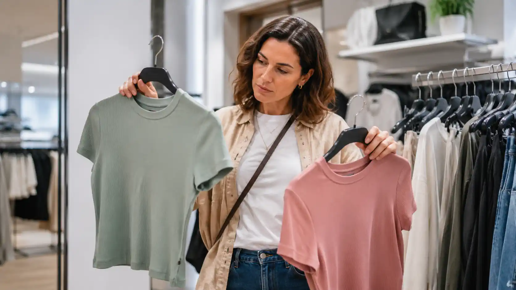 Femme comparant deux vêtements en boutique pour choisir sa taille