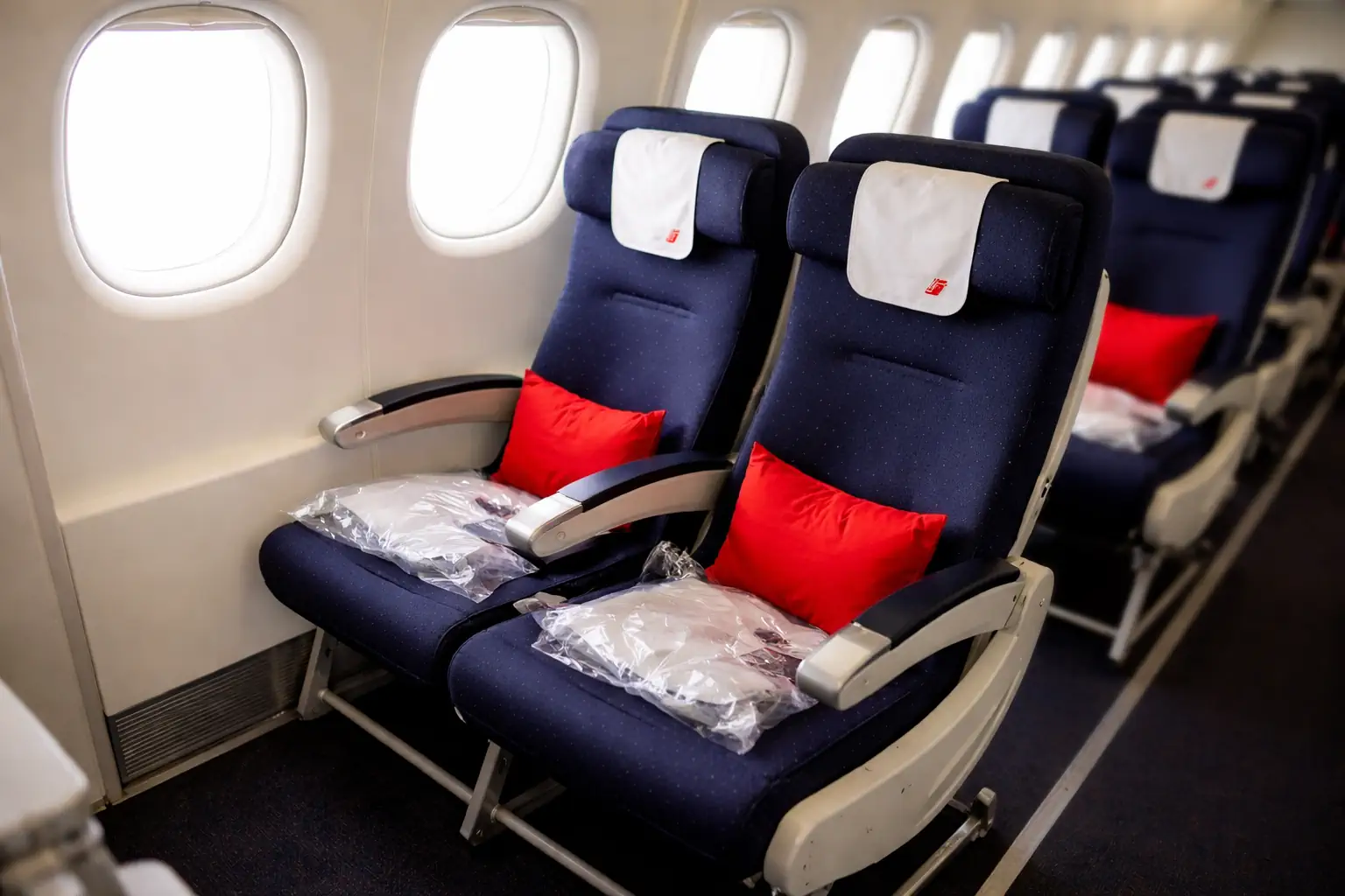 Deux sièges Duo Air France en cabine Economy long-courrier, côté hublot, avec coussins rouges et lumière de jour