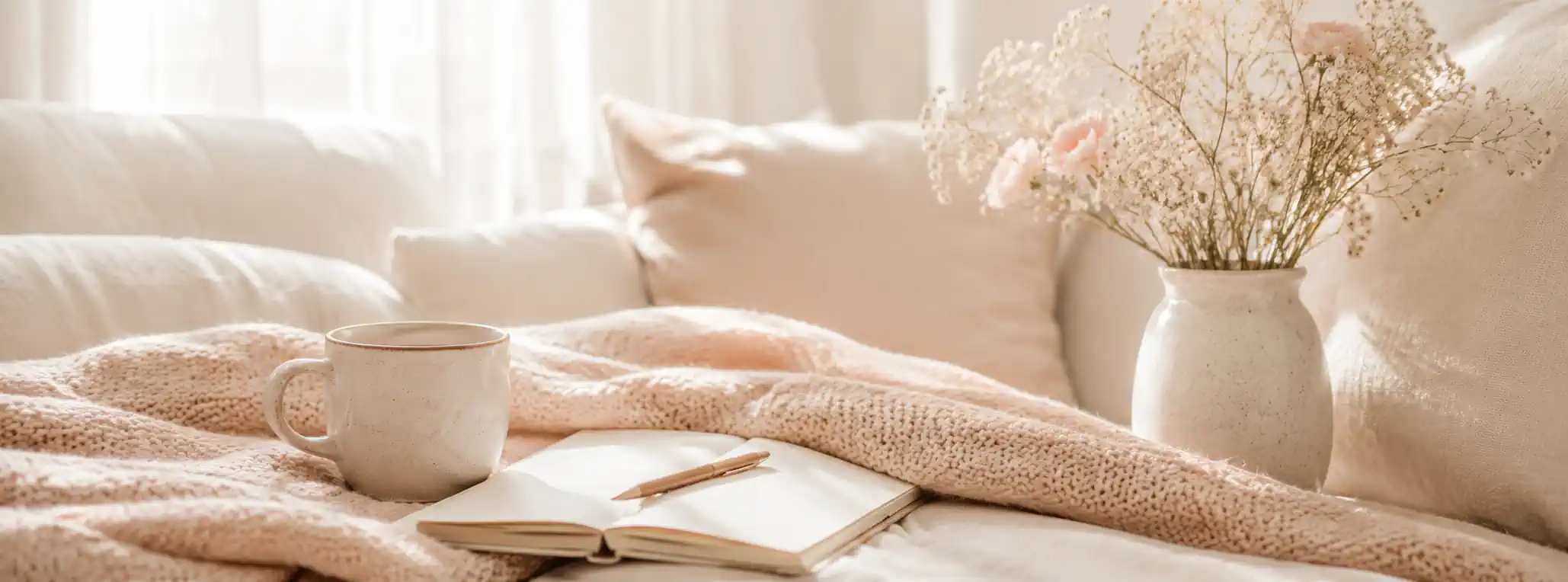 Coin cosy lumineux avec plaid, carnet ouvert, tasse et lumière naturelle dans une ambiance douce