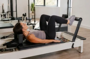 Femme réalisant un exercice de Pilates Reformer dans un studio lumineux